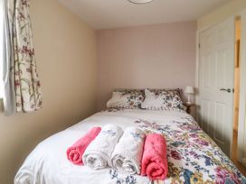 A bedroom with a bed with floral bedding towels on the bed and a lamp on a bedside table at The Old Hen Shed in Hainworth near Haworth