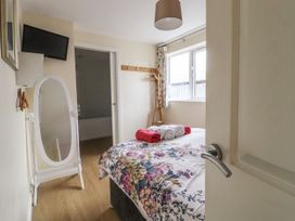 A bedroom with a bed with floral bedding towels on top a mirror and a window at The Old Hen Shed in Hainworth near Haworth