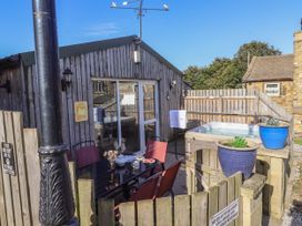 An outdoor patio area with a table and chairs a hot tub and potted plants at The Old Hen Shed in Hainworth near Haworth
