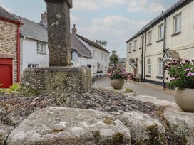 A street with a stone cross and flower pots at Trelan in Mevagissey