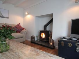 A living room with a fireplace and a television at Trelan in Mevagissey