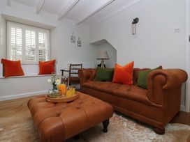 A living room with a leather couch and an ottoman at Trelan in Mevagissey