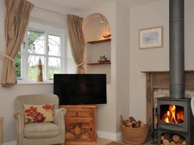 A living room with a tv and a wood burner at Stocks Barn Looe