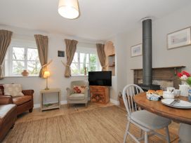 A living room with a sofa, armchair, and dining table at Stocks Barn Looe