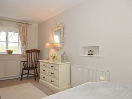 A bedroom with a dresser and chair at Stocks Barn in Looe