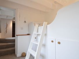 A staircase with a ladder and shelf at Stocks Barn in Looe