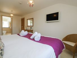 A bedroom with a bed, towels, television, and a mirror at Ridgeback House in Mullion