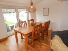 A dining room with wooden table and chairs near glass doors at Anneth Lowen in Angarrack near Hayle