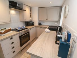 A kitchen with beige cabinets a microwave a stove oven a sink a toaster a knife block and a basket on the counter at Anneth Lowen Angarrack near Hayle