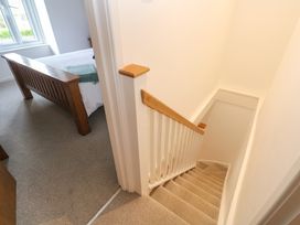 A staircase with wooden handrail next to a bedroom with a wooden bed frame at Anneth Lowen in Angarrack near Hayle