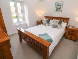 A bedroom with a wooden bed and bedside tables with lamps at Anneth Lowen in Angarrack near Hayle