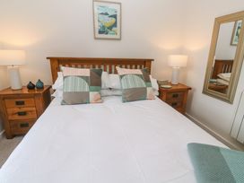 A bedroom with a wooden bed and two patterned cushions two bedside tables with lamps and a mirror on the wall at Anneth Lowen in Angarrack near Hayle