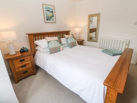A bedroom with a wooden double bed two bedside tables with lamps a wall mirror and a framed picture at Anneth Lowen Angarrack near Hayle