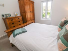 A bedroom with a wooden bed and dresser beside a window at Anneth Lowen in Angarrack near Hayle