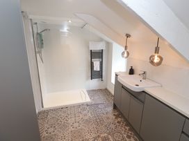 A bathroom with a walk-in shower sink with cabinet pendant lights and patterned floor tiles at Anneth Lowen in Angarrack near Hayle