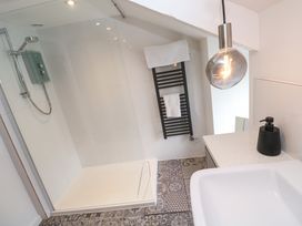A bathroom with a walk-in shower a black towel rack with towels a sink and a pendant light at Anneth Lowen Angarrack near Hayle