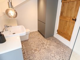 A bathroom with a patterned tiled floor a white sink gray cabinets and a wooden door at Anneth Lowen in Angarrack near Hayle