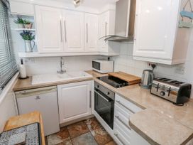 A kitchen with appliances and cabinets at Trelessy Lodge in Llanteg near Amroth