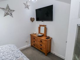 A bedroom with a dresser and television at Trelessy Lodge in Llanteg near Amroth