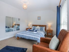 A bedroom with a bed and armchair at Bythynnod Newydd Trefor near Nefyn