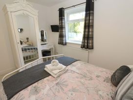 A bedroom with a bed and a mirror at Blacksmiths Cottage in Shilbottle