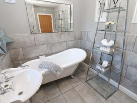 A bathroom with a bathtub and sink at Blacksmiths Cottage in Shilbottle