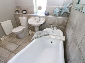A bathroom with a bathtub sink and toilet at Blacksmiths Cottage in Shilbottle