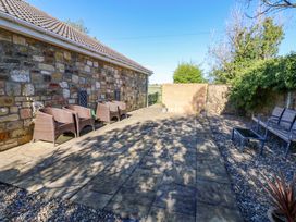 A garden with stone walls and seating areas at Blacksmiths Cottage in Shilbottle