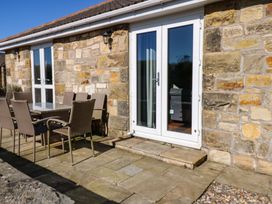 An outdoor patio with a table and chairs at Blacksmiths Cottage in Shilbottle