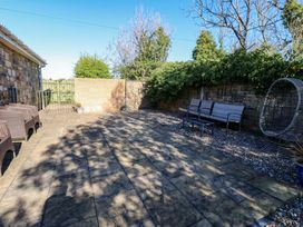 A garden patio area with seating and a wall at Blacksmiths Cottage in Shilbottle