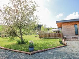 A garden area with a tree and potted plants next to a wooden building at No1 The Lodge in Acton near Bishop's Castle