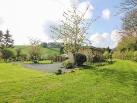 A grassy garden area with trees and a small wooden building at No1 The Lodge Acton near Bishops Castle