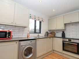 A kitchen with microwave washing machine and sink at Fieldside in Hunmanby