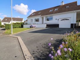 A house with a garage and flower bed at Bay View in Benllech