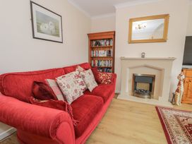 A living room with a red sofa and bookshelf at Bay View in Benllech