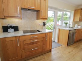 A kitchen with wooden cabinets and a sink at Bay View in Benllech