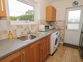 A kitchen with a sink, washing machine, and microwave at Bay View in Benllech