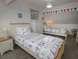 A bedroom with two beds and a dresser at Bay View in Benllech