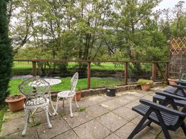 A garden with seating area and view of a stream at River's Nook in Llangynog