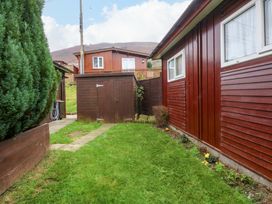 A garden with grass and a shed at River's Nook in Llangynog