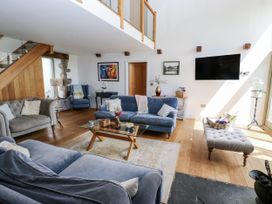 A living room with a television and staircase at Crane Field Laithe in Otterburn, North Yorkshire