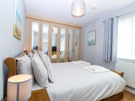 A bedroom with a bed and wardrobe at Beach House (Ty Traeth) Deganwy