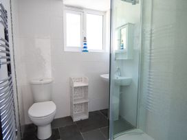 A bathroom with a toilet, sink, shower and shelf at Easterly Cottage in Bude
