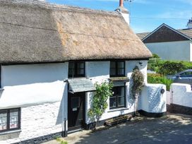 A thatched roof cottage with a door and windows at Easterly Cottage in Bude