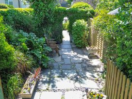 A garden with a stone pathway and wooden chair at Easterly Cottage in Bude