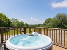 A hot tub with a bottle and towel in outdoor area at Costentyn, Tor Down Quarry St Breward