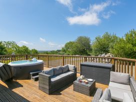 A seating area with a hot tub on a wooden deck at Costentyn, Tor Down Quarry St Breward
