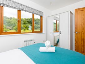 A bedroom with a bed, wardrobe, and windows at Tressa, Tor Down Quarry St Breward
