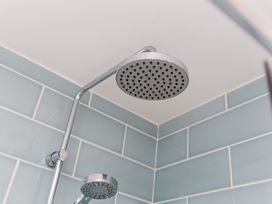 A shower head and arm in a bathroom at Tressa, Tor Down Quarry St Breward