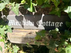A sign reading 'Meadow Cottage' surrounded by ivy at Meadow Cottage in Golant, near Fowey